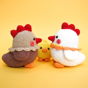 Op de afbeelding: Drie gehaakte knuffels van kippen. Eén is bruin met een rode kam, één is wit met een rode kam en één is geel met een gele snavel.