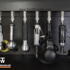 May include: A collection of nine silver and black air tools hanging on a black wall rack. The tools are labelled "Tool Wrangler" and the website "www.ToolWrangler.com" is displayed at the top of the image.
