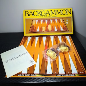 May include: A complete Backgammon game set with a yellow and brown game board, dice, and game pieces. The box reads "BACKGAMMON" and "FOR 2 PLAYERS - AGES 7 TO ADULT". Includes a rule book and game pieces.