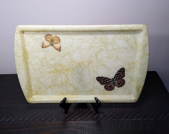 May include: A rectangular serving tray with a light yellow background and a delicate, marbled pattern. Two butterflies are painted on the tray, one in brown and black and the other in brown and yellow.