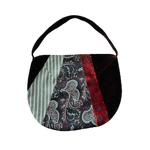 May include: A patchwork shoulder bag with a black handle. The bag features panels of striped fabric, paisley print, and dark red velvet. The bag has a rounded shape and a single shoulder strap.