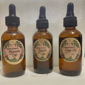 May include: Three amber glass bottles with dropper tops and labels. The labels are brown with white text and a floral design. The bottles are labeled "Migraine Oil", "Health Oil", and "Sleep Oil".