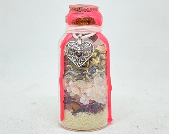 May include: A small glass bottle with a pink wax seal and a silver heart charm. The bottle is filled with layers of dried herbs, flowers, and crystals.