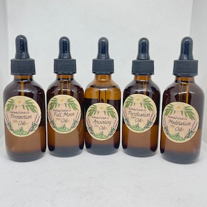 May include: Five amber glass bottles with black dropper tops and labels. The labels are round and feature a floral design with the text "The Mindful Witch Co." and the name of the oil: "Protection Oil", "Full Moon Oil", "Anointing Oil", "Purification Oil", and "Meditation Oil".
