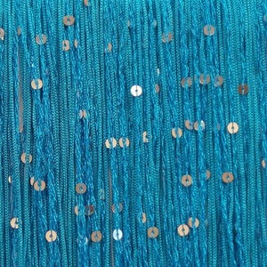 May include: Close-up of turquoise fringe with gold sequins. The fringe is made of many strands of turquoise thread, with small, round gold sequins evenly spaced throughout. The top edge is a solid turquoise band.