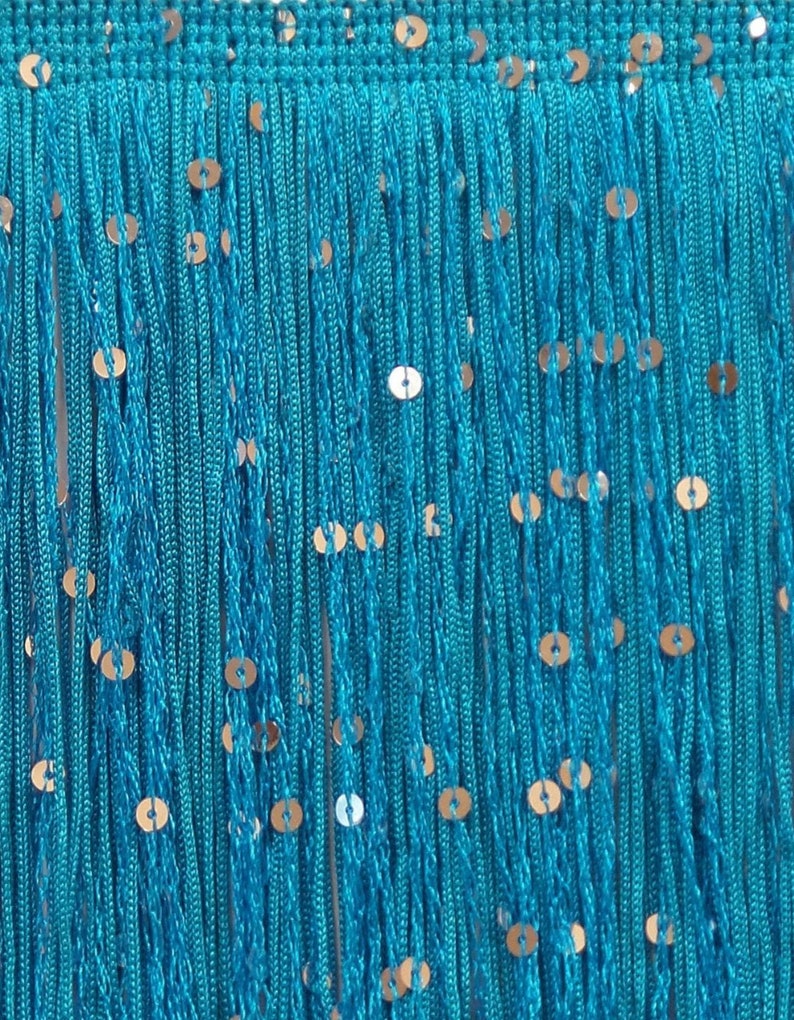 May include: Close-up of turquoise fringe with gold sequins. The fringe is made of many strands of turquoise thread, with small, round gold sequins evenly spaced throughout. The top edge is a solid turquoise band.