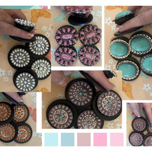 May include: A collage of decorative phone grips in various designs. The grips feature black bases with different colored stones and embellishments, including white, pink, turquoise, and orange. Some grips are held by a hand.