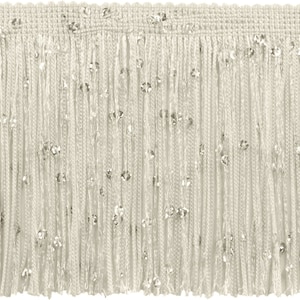 May include: Ivory fringe trim with scattered silver sequins. The trim features a woven top edge and long, dangling strands of fringe. This decorative trim is suitable for embellishing clothing, accessories, or home decor projects.