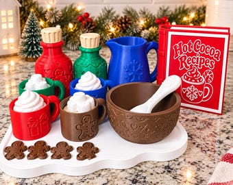 Op de afbeelding: Een speelgoedset voor warme chocolademelk met een rood receptenboek met de tekst Hot Cocoa Recipes, een blauwe kan, rode en groene flessen met beige doppen, drie mokken met witte slagroom, een bruine kom, een witte lepel en vier peperkoekmannetjes.