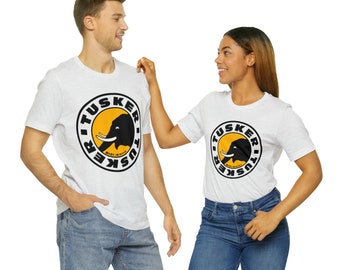 May include: Two people wearing white t-shirts with a black and yellow logo featuring an elephant and the text "Tusker" in a circle. The logo is repeated on both shirts. The person on the left is wearing blue jeans. The person on the right is wearing blue jeans.