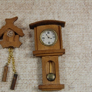 May include: Two wooden clocks, one a traditional cuckoo clock with a gold chain and the other a grandfather clock with a pendulum.