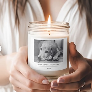 a woman holding a candle with a picture of a dog on it