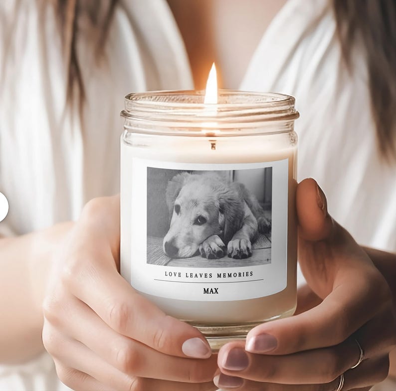 a woman holding a candle with a picture of a dog on it