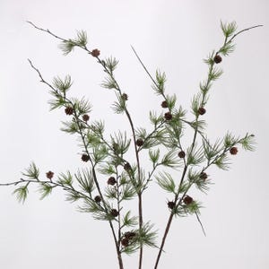 May include: A decorative artificial branch featuring thin, dark brown stems with clusters of soft, needle-like green foliage and small, round, dark brown pinecones distributed throughout the length of the branches against a plain background.