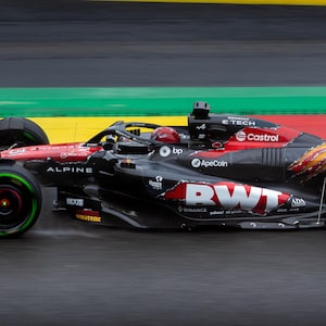 Puede incluir: Un coche de carreras negro y rojo con las palabras "Alpine", "Castrol", "RWT" y "ApeCoin" en él. El coche está en una pista de carreras.