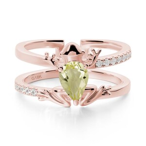 May include: Rose gold ring with a pear-shaped, light green gemstone. The ring features a double band design, with small white gemstones set along the top band. The ring is marked with "G18K".