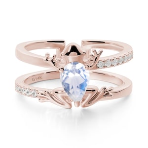 May include: Rose gold ring featuring a pear-shaped, light blue gemstone. The ring has a double band design, with one band set with small, clear stones. The ring has a nature-inspired design with antler-like details and the inscription "G14K".