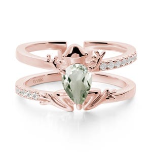 May include: Rose gold ring featuring a pear-shaped green gemstone and small white gemstones. The ring has an antler design and the text "G18K".