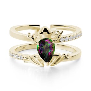 May include: A two-piece gold-coloured ring set. The top ring features a row of small, clear stones. The bottom ring has a pear-shaped, multi-coloured gemstone. The rings are adorned with decorative elements. The inscription "G14K" is visible on the bottom ring.