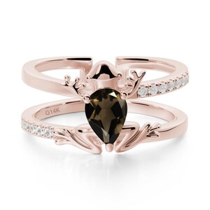 May include: Rose gold ring with a pear-shaped, dark brown gemstone. The ring features a deer antler design and small white gemstones. The band is split into two parts, with the inscription "G14K" visible on the lower band.