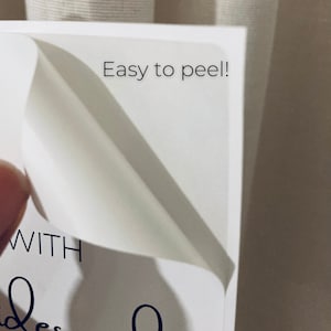 May include: Close-up of a white sticker with the text "Easy to peel!" and part of a handwritten script. The sticker is being peeled back, revealing a clean, white surface. The image suggests a product with easy-to-use labels.