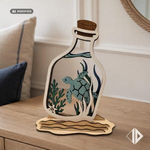 May include: A layered wooden cutout shaped like a bottle with a cork stopper. Inside the bottle, a light blue sea turtle swims among dark green seaweed and coral. The entire structure rests on a tan, wavy base representing sand or ocean waves.