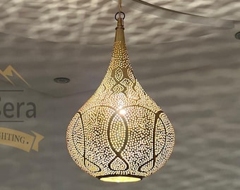 Könnte beinhalten: Eine goldene marokkanische Pendelleuchte in Tropfenform mit filigranen Ausschnitten. Die Leuchte hängt an einer Kette und hat eine weiße Deckenbefestigung.