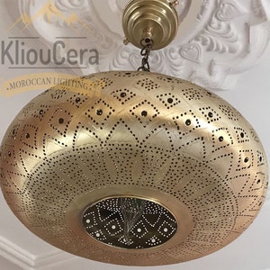 May include: A gold Moroccan pendant light with a round, perforated shade featuring a geometric pattern. The light is hanging from a chain.