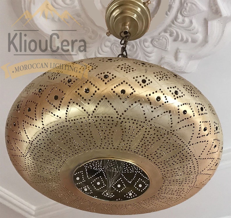 May include: A gold Moroccan pendant light with a round, perforated shade featuring a geometric pattern. The light is hanging from a chain.