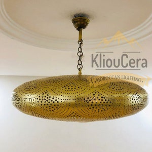 May include: A gold-toned, round, Moroccan-style ceiling light fixture with a decorative, perforated design. The light fixture is suspended from the ceiling by a chain.