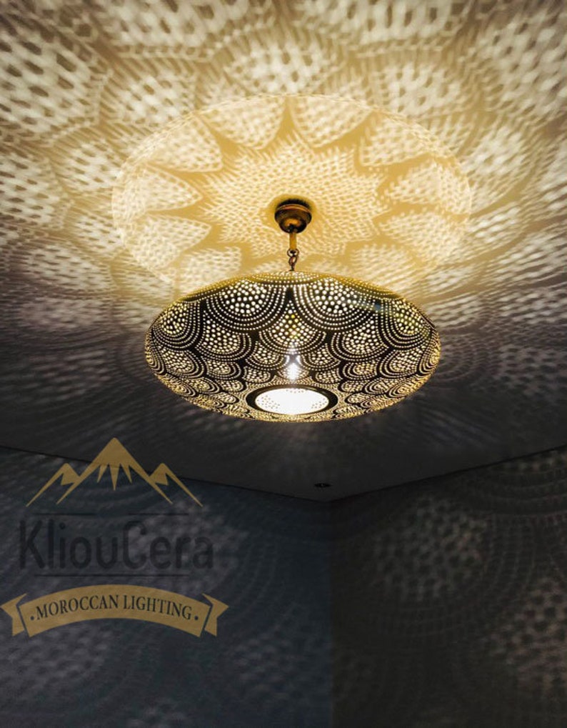 May include: A gold Moroccan pendant light with a circular, patterned shade. The light casts a geometric shadow on the ceiling.