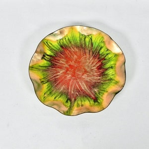 May include: A round, scalloped copper tray with a green, red, and gold abstract design. The tray is perfect for serving snacks or holding jewelry.