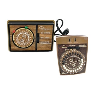 May include: Two vintage electric timers with wood-effect and brown plastic casings. One has a round dial with day and night settings, the other a square face with a similar dial. Both feature the brand name "Engraham".