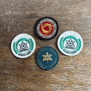 Könnte beinhalten: Vier Vintage-Stickabzeichen. Ein schwarzes Abzeichen mit rotem und goldenem Text lautet "Fitness Award Canada Prix D'efficience Physique". Zwei weiße Abzeichen mit grüner Umrandung lauten "North York 1867-1967". Ein blaues Abzeichen lautet "Centennial Athlete Du Centenaire".