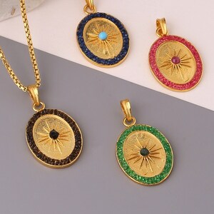 May include: A gold chain necklace with a pendant featuring a sunburst design with a black centre stone. Three additional pendants are shown with different coloured centre stones: blue, red and green.