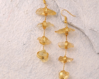 May include: A pair of gold earrings with multiple yellow crystal stones hanging from gold chains. The earrings are designed with a simple hook closure.
