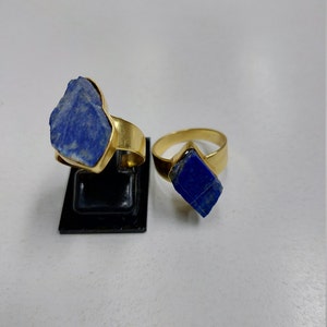 May include: Two gold rings with blue lapis lazuli stones. The stones are rough and irregular in shape.