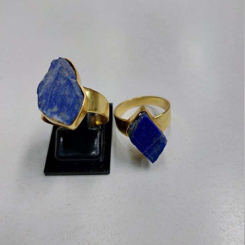 May include: Two gold rings with blue lapis lazuli stones. The stones are rough and irregular in shape.