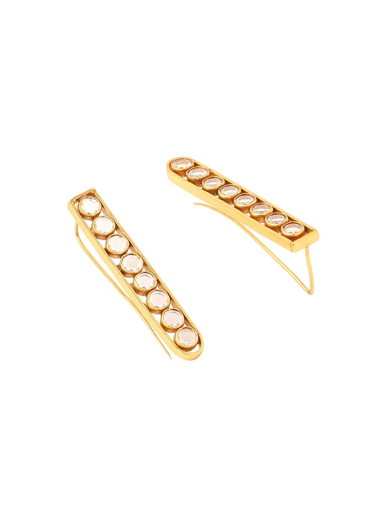 May include: A pair of gold earrings with a row of clear round stones. The earrings are long and thin, and the stones are set in a gold frame.