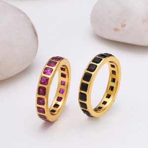 Peut inclure: Deux bagues en or avec une bande de pierres précieuses de forme carrée. Une bague a des pierres précieuses roses et l'autre a des pierres précieuses noires.