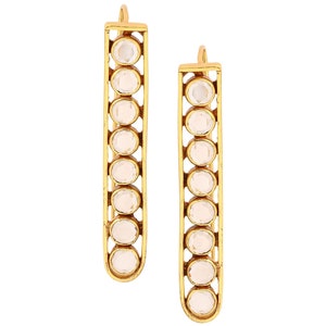 May include: A pair of gold earrings with clear stones. The earrings are long and rectangular in shape, with a row of stones down the center.