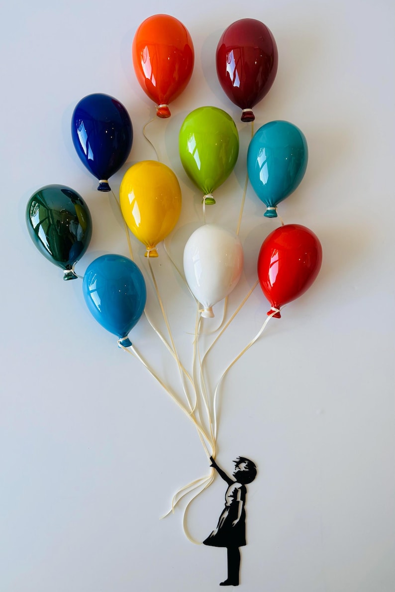 May include: A colorful wall art piece featuring a cluster of glossy, balloon-shaped sculptures in various colors, including red, blue, and green. A silhouette of a child holding the balloon strings is attached to the wall.