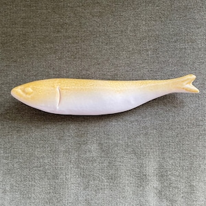 May include: A ceramic fish shaped dish with a light pink and yellow glaze. The dish is a light yellow on the top and a light pink on the bottom.