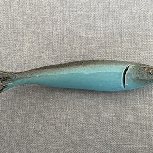 May include: A ceramic blue and brown fish figurine. The fish is glazed in a light blue colour with brown accents.