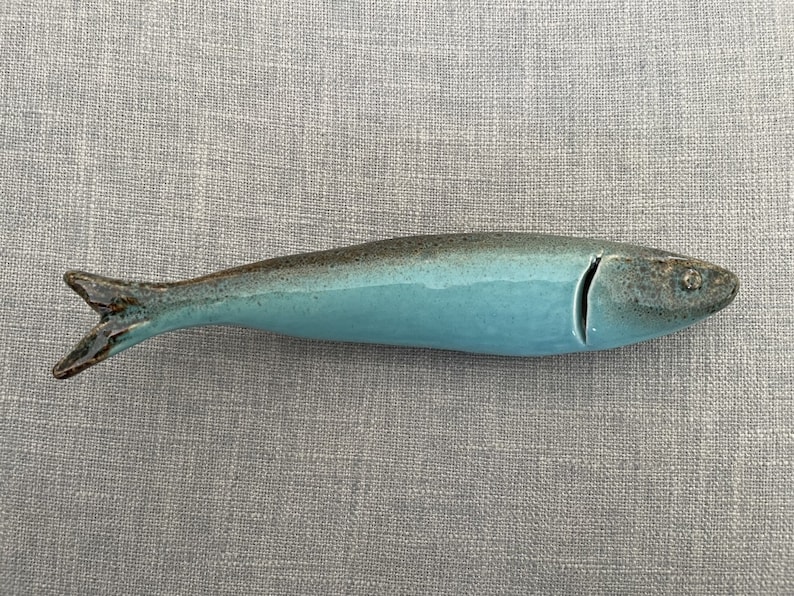 May include: A ceramic blue and brown fish figurine. The fish is glazed in a light blue colour with brown accents.