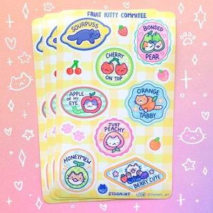 May include: A set of 10 colourful stickers featuring cartoon cats dressed as different fruits. Each sticker has a punny name and a cute illustration. The stickers are on a yellow and white chequered background.