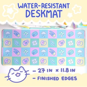 May include: A water-resistant desk mat with a checkered pattern featuring pastel pink, blue, and green squares. Each square has a different cute cartoon design, including mushrooms, snails, beetles, and raindrops. The mat is 68.6 cm by 30 cm and has finished edges.
