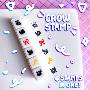 Puede incluir: Un juego de seis sellos cuadrados blancos con diseños de cuervos negros, lazos rojos y llaves amarillas. El texto "CROW STAMP" y "6 STAMPS IN ONE!" se muestran en una fuente lúdica. El fondo es blanco con elementos decorativos.