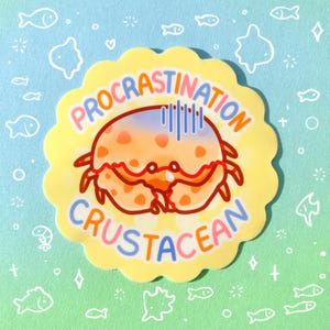 May include: A yellow sticker with a scalloped edge featuring a cartoon crab with the text "PROCRATINATION CRUSTACEAN". The crab is orange with blue and orange accents, and the text is in various colors.