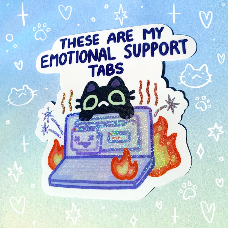 May include: A sticker with a black cat sitting on a laptop with flames coming out of the sides. The text on the sticker reads "These are my emotional support tabs".